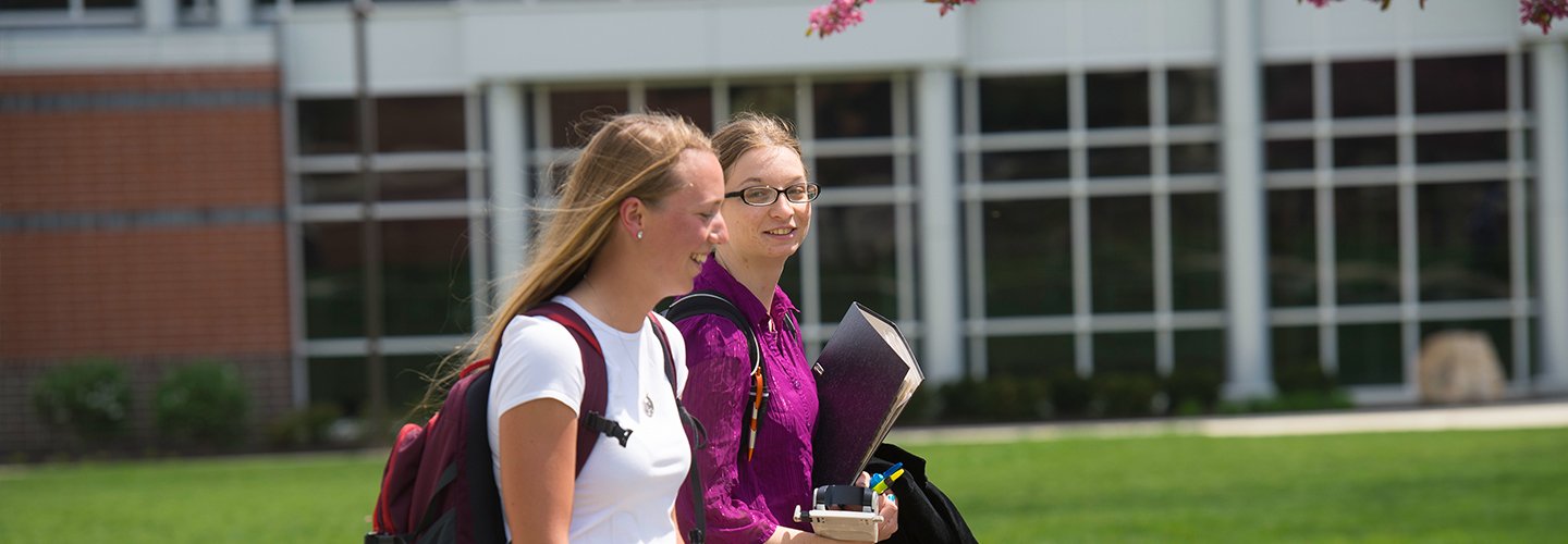 Two students walking together between classes on campus.